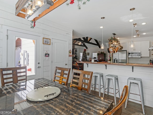 dining space featuring dark wood-type flooring and wooden walls