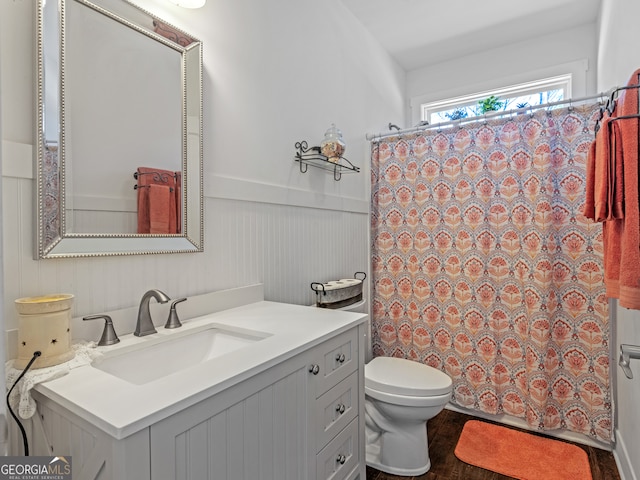 bathroom featuring hardwood / wood-style floors, walk in shower, toilet, and vanity