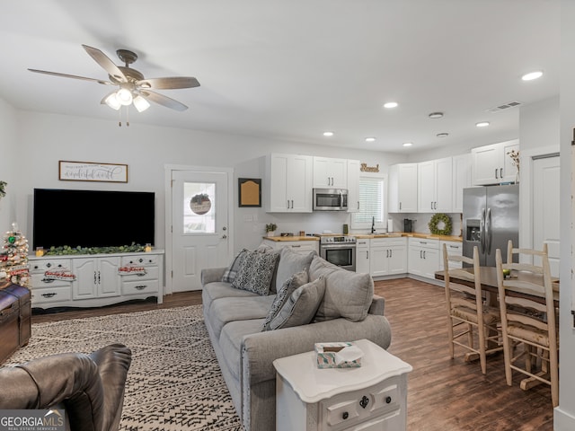 living room featuring dark wood-type flooring, ceiling fan, plenty of natural light, and sink