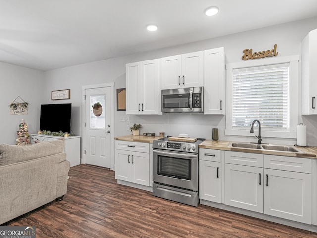 kitchen with wooden counters, appliances with stainless steel finishes, and white cabinets