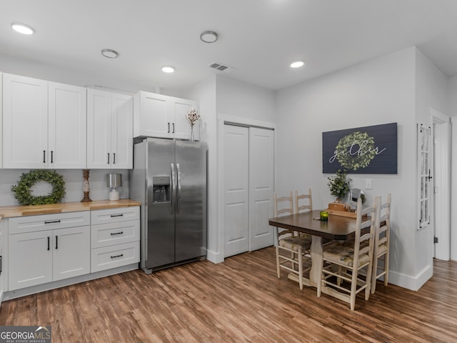 kitchen with butcher block countertops, stainless steel fridge, hardwood / wood-style flooring, and white cabinetry