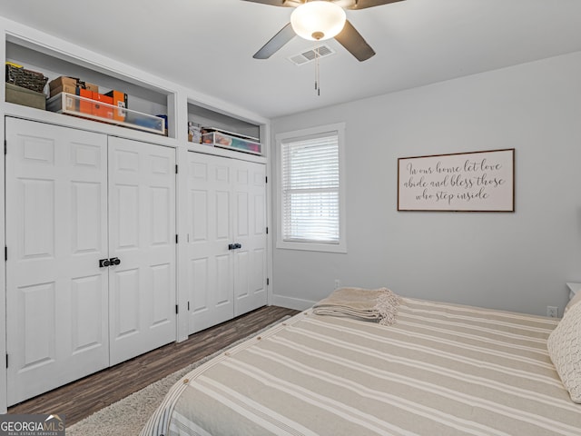 bedroom featuring multiple closets, ceiling fan, and dark hardwood / wood-style floors