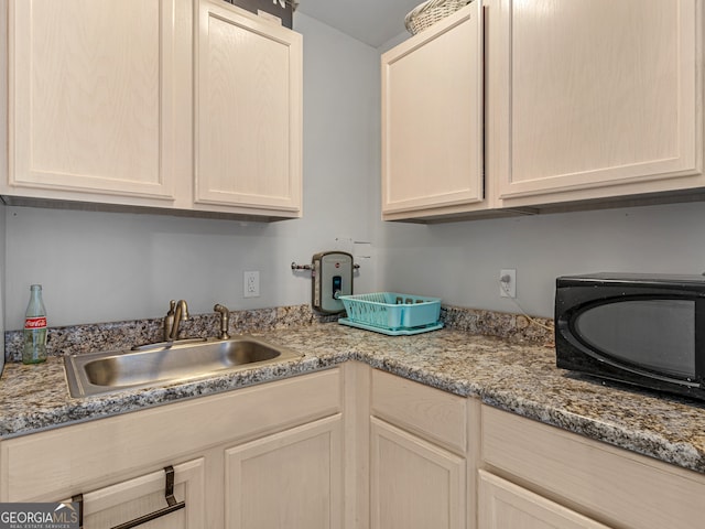 kitchen with light stone countertops, sink, and light brown cabinets