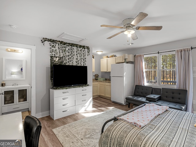 bedroom featuring light hardwood / wood-style flooring, ceiling fan, white refrigerator, and connected bathroom