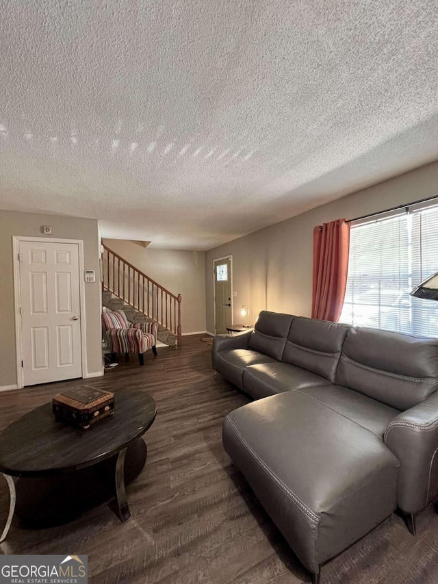 living room with a textured ceiling and dark hardwood / wood-style floors