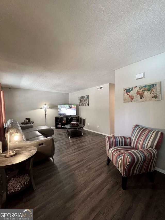 living room featuring dark wood-type flooring and a textured ceiling