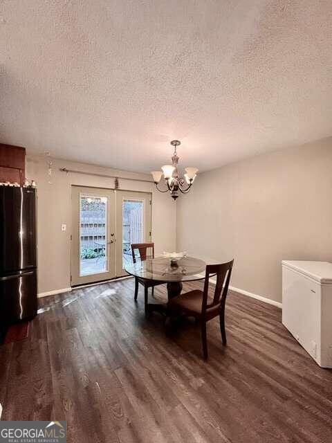 unfurnished dining area featuring dark wood-type flooring, a textured ceiling, and a chandelier