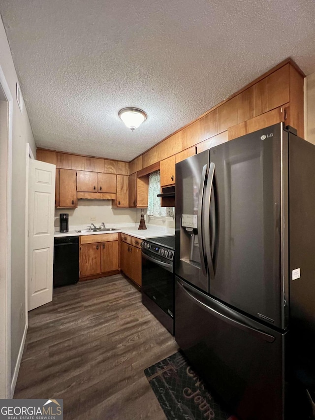 kitchen featuring black appliances, dark wood-type flooring, sink, and a textured ceiling