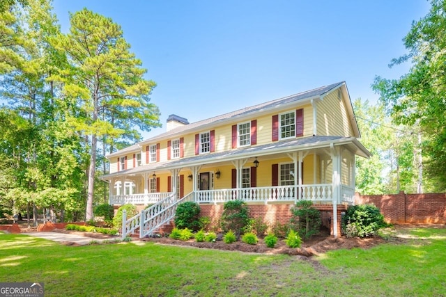 colonial house with stairs, a chimney, covered porch, fence, and a front lawn