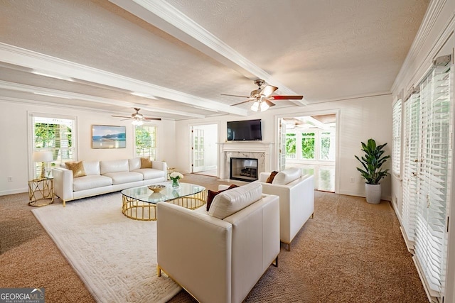 living room featuring a textured ceiling, crown molding, light colored carpet, and a glass covered fireplace