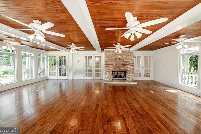 unfurnished living room featuring ceiling fan, french doors, wood-type flooring, a stone fireplace, and wooden ceiling