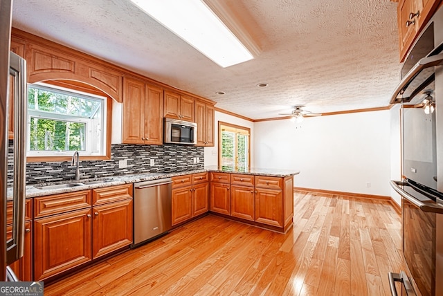 kitchen featuring ceiling fan, appliances with stainless steel finishes, light wood-type flooring, and kitchen peninsula