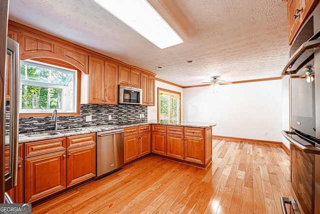 3060 Orchard Rd SW, Conyers, GA 30094 - kitchen featuring stainless steel appliances, a textured ceiling, a peninsula, brown cabinets, and ornamental molding