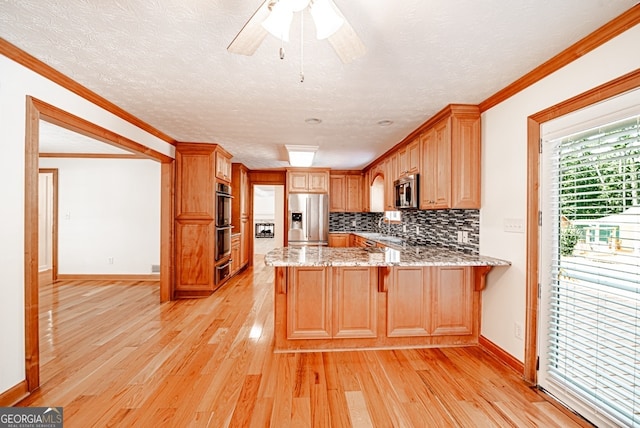 kitchen featuring ceiling fan, kitchen peninsula, appliances with stainless steel finishes, crown molding, and light hardwood / wood-style floors