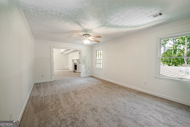 spare room featuring ceiling fan, a textured ceiling, light carpet, and crown molding