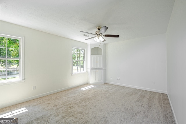 empty room with ceiling fan, carpet floors, and a wealth of natural light