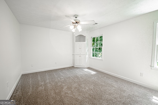 unfurnished room with carpet, ceiling fan, and a textured ceiling