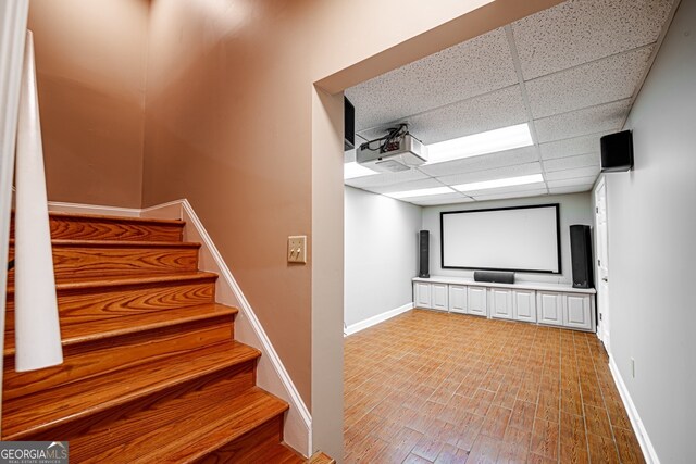 home theater room featuring a drop ceiling and hardwood / wood-style flooring