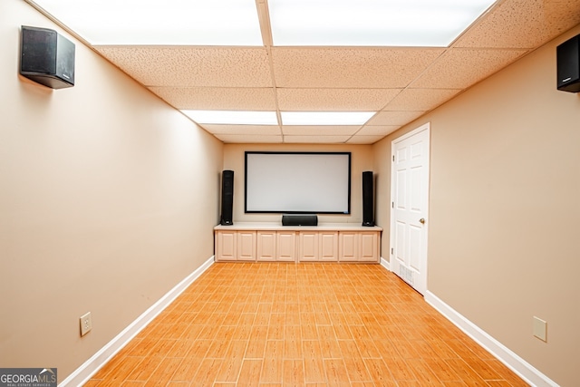 home theater with light wood-type flooring and a drop ceiling