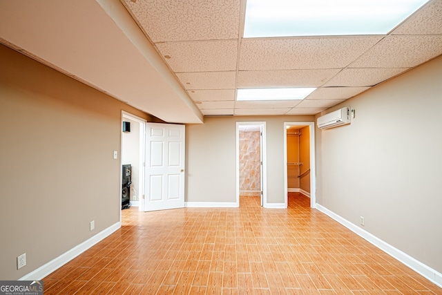 spare room with light wood-type flooring, a drop ceiling, and a wall mounted AC