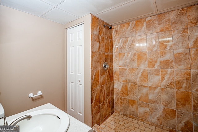 bathroom with toilet, sink, and a tile shower