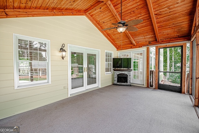 unfurnished sunroom featuring a stone fireplace, vaulted ceiling with beams, wood ceiling, and ceiling fan