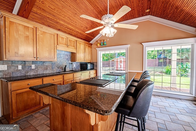 kitchen featuring ceiling fan, lofted ceiling, plenty of natural light, and a kitchen breakfast bar