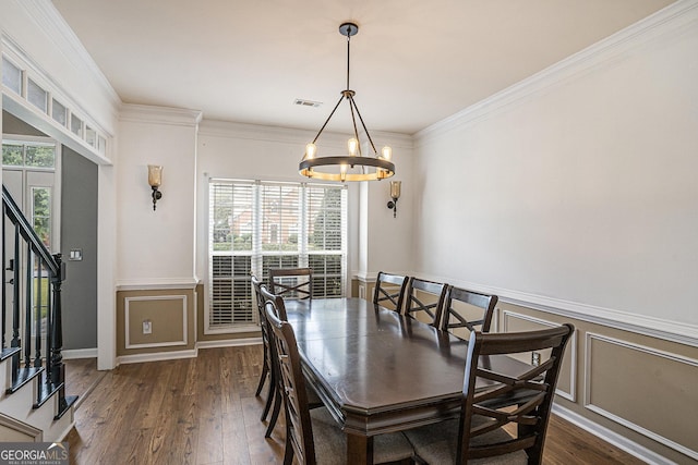 dining room featuring dark wood-type flooring, a notable chandelier, and ornamental molding