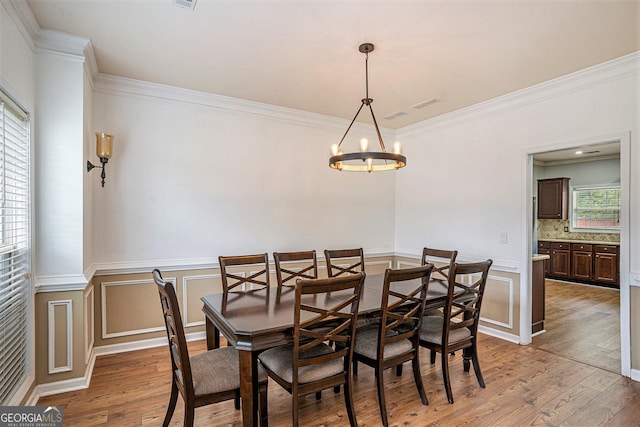 dining room with light hardwood / wood-style floors, a notable chandelier, and ornamental molding