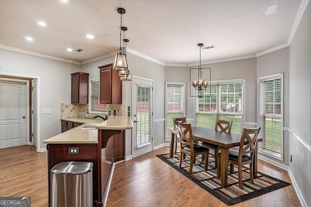 kitchen featuring light wood-type flooring, ornamental molding, sink, and a chandelier