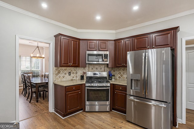 kitchen with light hardwood / wood-style flooring, light stone countertops, appliances with stainless steel finishes, tasteful backsplash, and a chandelier