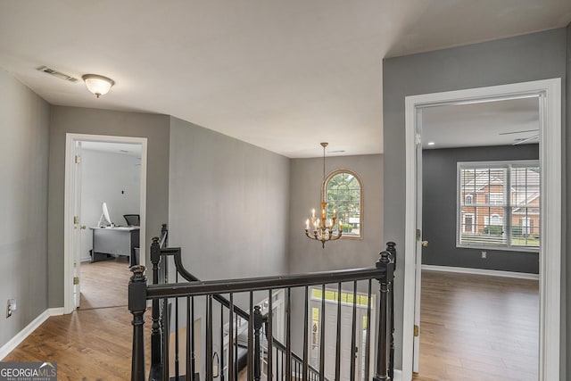 hall featuring hardwood / wood-style flooring and an inviting chandelier