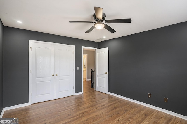 unfurnished bedroom featuring hardwood / wood-style flooring, ceiling fan, and a closet