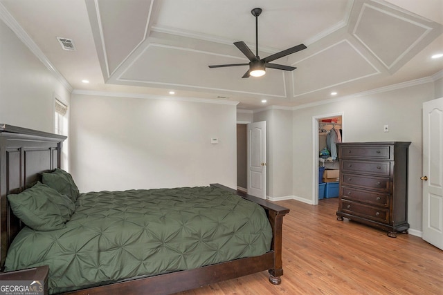 bedroom featuring ceiling fan, crown molding, a walk in closet, a closet, and light wood-type flooring