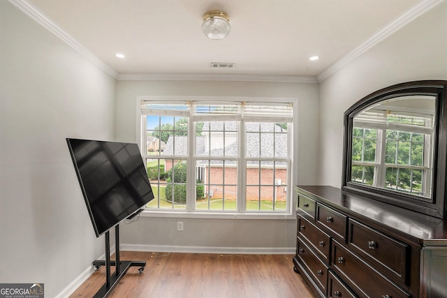 exercise area featuring light hardwood / wood-style flooring and ornamental molding