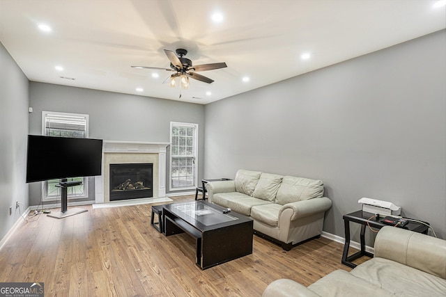 living room featuring ceiling fan, plenty of natural light, a high end fireplace, and light hardwood / wood-style flooring