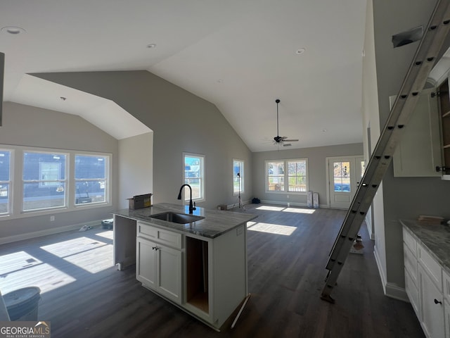 kitchen with light stone countertops, ceiling fan, sink, a center island with sink, and white cabinets