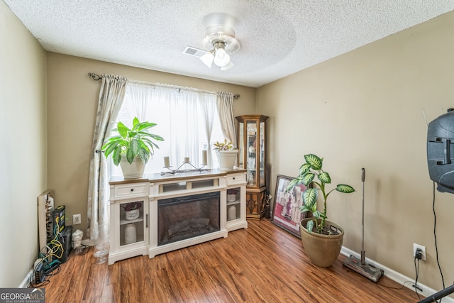 living room featuring a textured ceiling, ceiling fan, and hardwood / wood-style floors