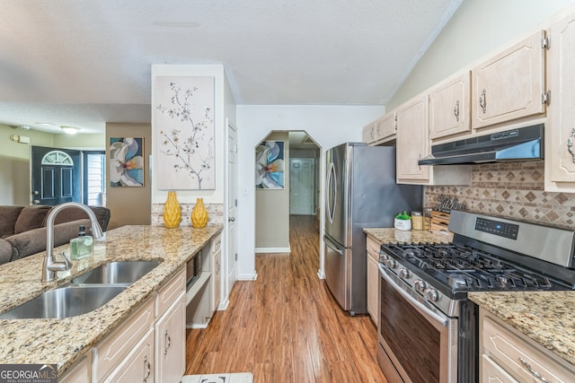 kitchen featuring a textured ceiling, light stone countertops, light hardwood / wood-style floors, stainless steel appliances, and sink