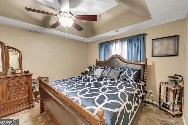 carpeted bedroom featuring a raised ceiling and ceiling fan