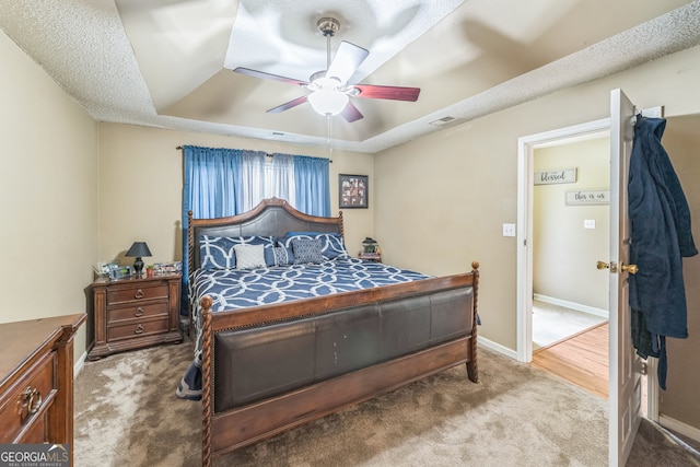 carpeted bedroom with a tray ceiling and ceiling fan