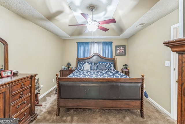 carpeted bedroom with ceiling fan and a tray ceiling