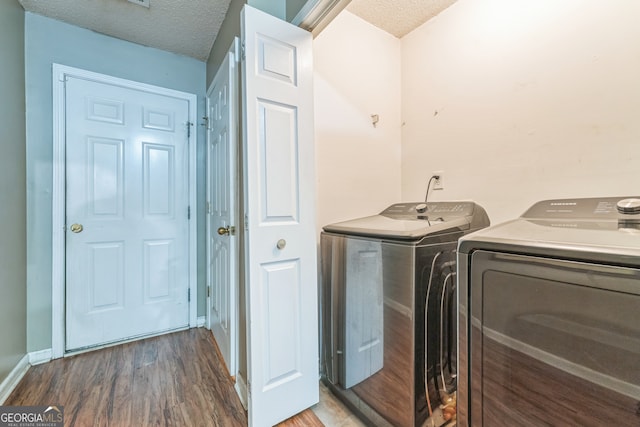 washroom featuring dark wood-type flooring, a textured ceiling, and washer and clothes dryer