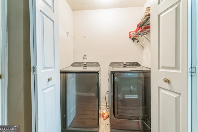 clothes washing area featuring a textured ceiling and washing machine and dryer