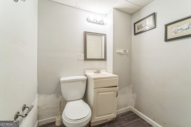 bathroom featuring toilet, a drop ceiling, and vanity