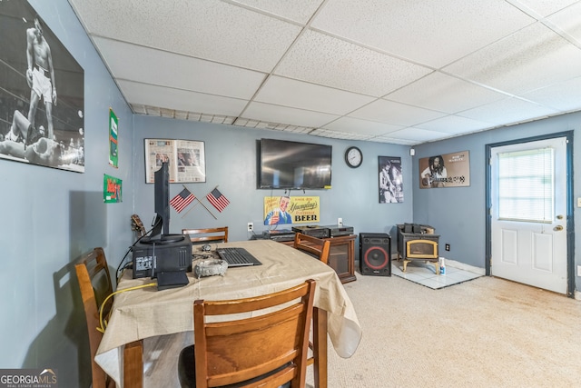 dining area featuring a wood stove, a paneled ceiling, and carpet floors