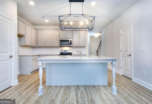 kitchen featuring light wood-type flooring, appliances with stainless steel finishes, and pendant lighting