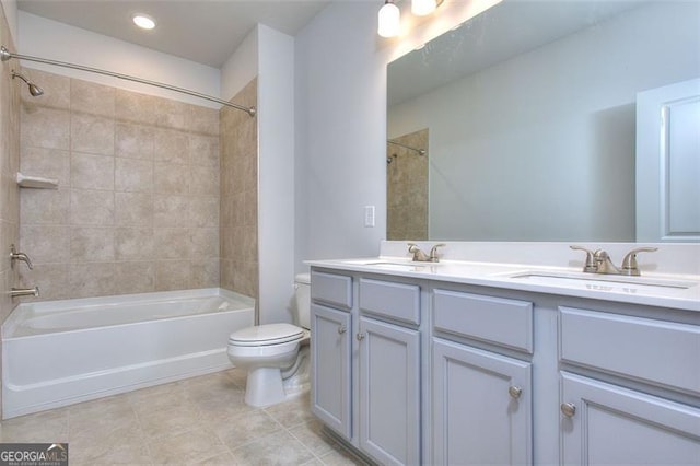 full bathroom with tile patterned flooring, toilet, tiled shower / bath combo, and vanity