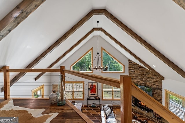 bonus room with hardwood / wood-style flooring, high vaulted ceiling, a wealth of natural light, and an inviting chandelier