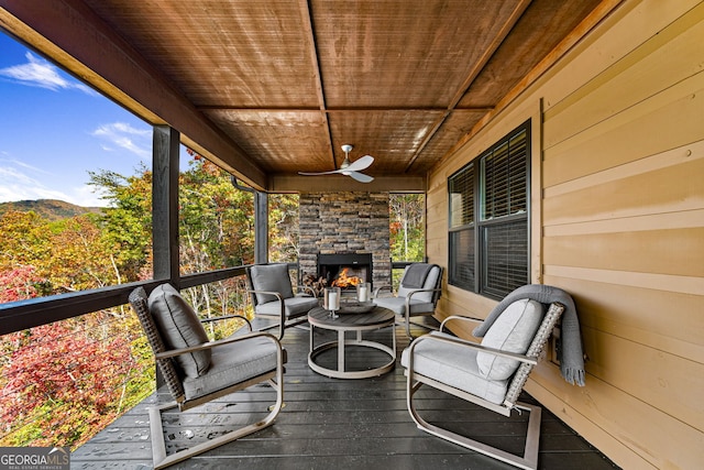 wooden deck with ceiling fan and an outdoor stone fireplace